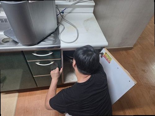 도봉구 누수탐지 싱크대 하부장 안쪽 급수관과 배수 트랩을 점검하는 모습